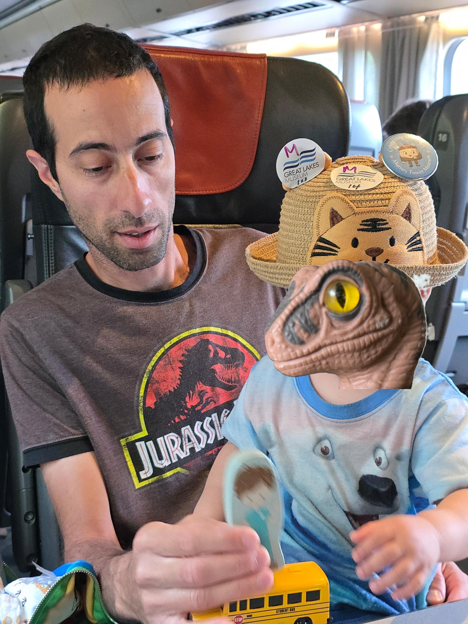 me and my kid sitting in the train, him playing with his toys, me wearing a Jurassic Park shirt